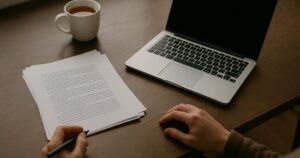Japanese manuscript pages and a laptop on a desk