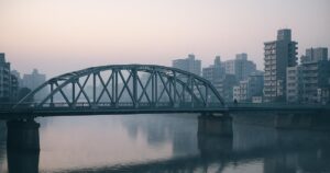 A steel bridge over a river in a Japanese city at dawn